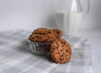 Close-up of homemade oatmeal cookies in a plate, in the background a jug of milk. Healthy breakfast and weight loss concept. copy space for text. selective focus