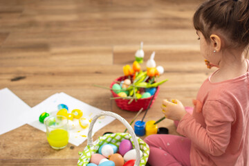 Obraz na płótnie Canvas Baby girl painting Easter eggs at home. Copy space