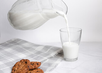 Fresh homemade milk is poured from a jug of milk. Selective focus of oatmeal cookies. Healthy breakfast and weight loss concept. copy space for text. Breakfast in the village. copy space for text