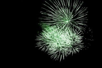 Luxury fireworks event sky show with green big bang stars. Premium entertainment magic star firework at e.g. New Years Eve or Independence Day party celebration. Black dark night background