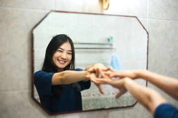 Young adult smile asian woman practice self talk conversation in the morning in bathroom at home.