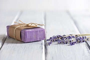 Lavender soap with dried lavender flowers on a white wooden table. Side view.
