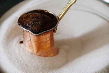 Brewing coffee in copper cezve on sand. Traditional turkish method