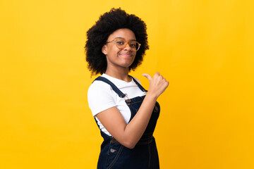 Young African American woman isolated on yellow background proud and self-satisfied