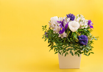 A bouquet of spring flowers on a yellow background. Flower composition. Valentines Day and spring concept. Copy space.
