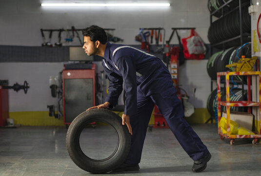 Mechanic carrying a tyre at a tyre service and repair center	