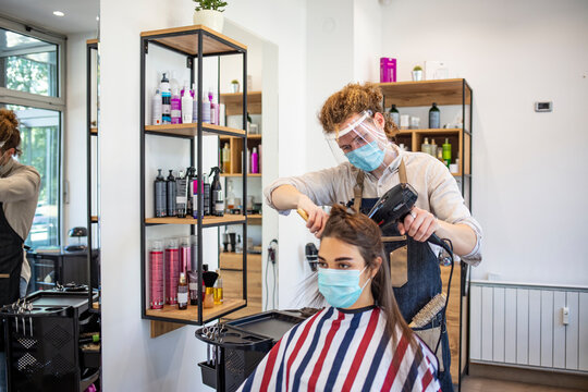Adult woman at hairdresser wearing protective mask due to coronavirus pandemic. Hairdressing salon opened. Hairdresser with security measures for Covid-19, a woman in a medical mask, social distance