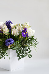 A bouquet of spring flowers in a box on a white background. Mothers Day and spring concept. Vertical orientation.