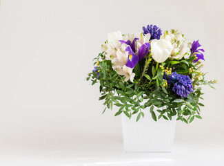 A bouquet of flowers in a white box on a white background. Spring flowers composition. Copy space. Floral design.
