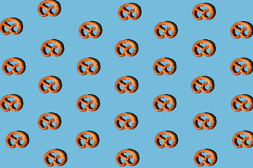 pattern of pretzels on a blue background properly arranged with a sharp light. minimal flat lay aesthetic