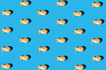 goldfish snack pattern on a blue background with a sharp light. minimal flat lay aesthetic