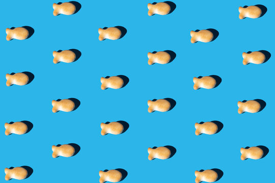 goldfish snack pattern on a blue background with a sharp light. minimal flat lay aesthetic