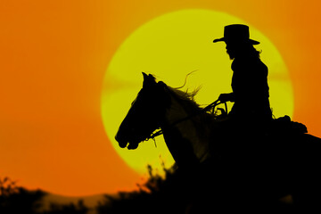 The silhouette of the cowboy and the setting sun - 418900363