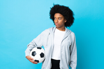 Young African American woman isolated on blue background with soccer ball