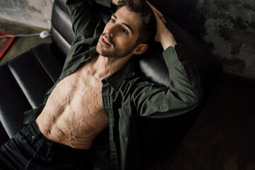 Smiling calm relaxed guy with scars at his chest lounge in cozy home. Self-acceptance concept
