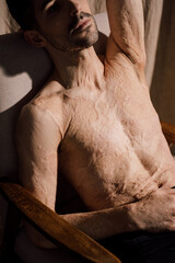 Calm young man with scars after burn relaxing while thinking
