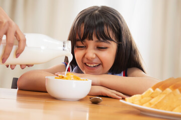 A HAPPY CHILD WAITING EAGERLY TO EAT CORNFLAKES WITH MILK	