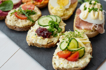selection board of open sandwiches dips, spreads, cold cut meat, cheese, egg and salad 