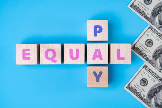 EQUAL PAY text on wooden blocks, daollars on blue background