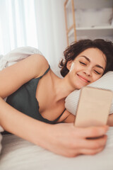 Happy brunette young woman using cellphone at home