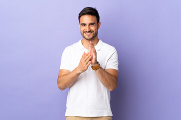 Young handsome man isolated on purple background applauding after presentation in a conference