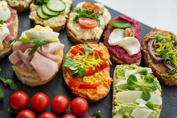 selection board of open sandwiches dips, spreads, cold cut meat, cheese, egg and salad 