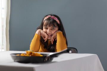 A YOUNG GIRL SITTING AND LOOKING AWAY WITH FOOD KEPT IN FRONT OF HER	
