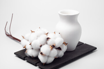 vase and bouquet of cotton on a wooden board