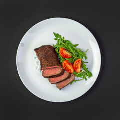 Medium fried steak with arugula and tomatoes