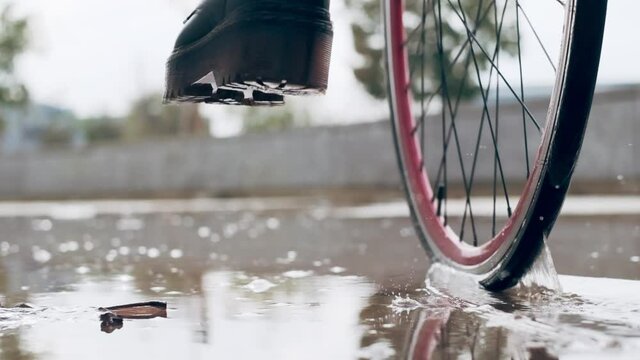 Cycling woman stepping in puddle, splashing water