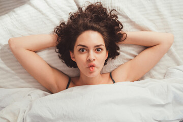 Fototapeta premium Woman making funny faces while enjoying lazy morning in her bed