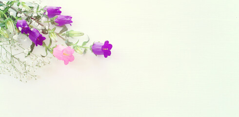 spring bouquet of purple, white and pink bell flowers over white wooden background
