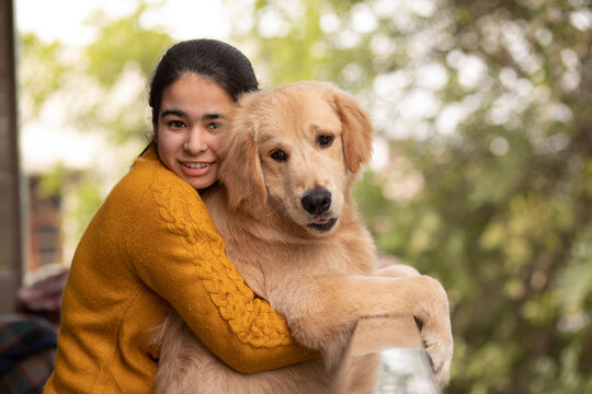 A YOUNG GIRL AND PET DOG LOOKING AT CAMERA AND POSING TOGETHER	