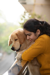 A PET DOG AND YOUNG GIRL LEANING OVER RAILING AND HAPPILY LOOKING DOWN	