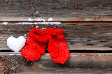 Obraz na płótnie Canvas Snow heart and red mittens on wooden surface, romanric holiday concept