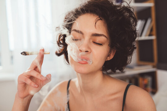 Woman spending time in bed at home while smoking marijuana