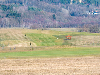 Obraz premium Resort golf course in the valley with bright green grass and naked leafless trees