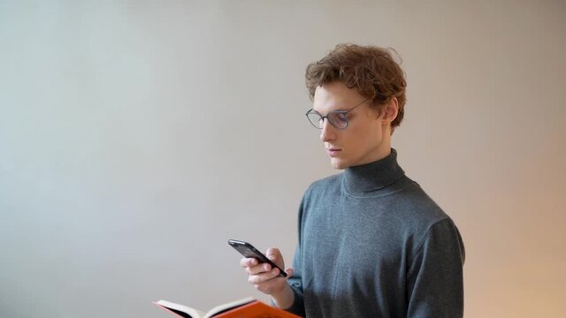 portrait of a handsome curly guy taking pictures of a book page