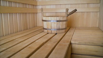 Fototapeta na wymiar Sauna Accessories In The Interior. Stylish wooden basin with a broom in the sauna. Wooden basin in the sauna.