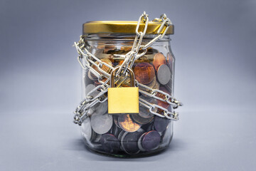 Fototapeta na wymiar Jar full of coins locked with chain, savings concept