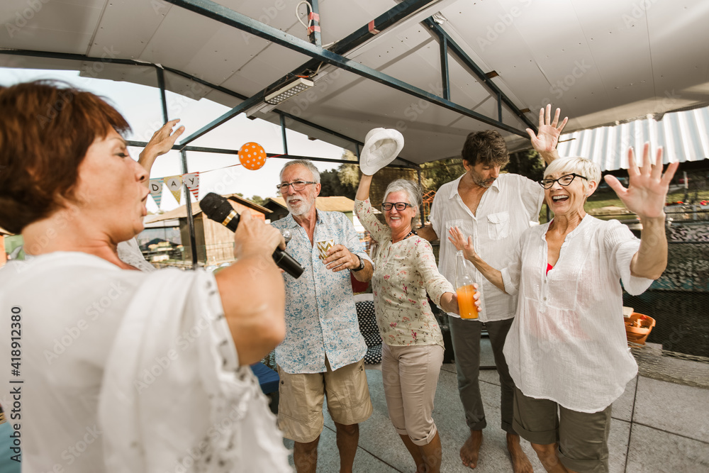 Wall mural senior people celebrating birthday in the cottage on the river singing karaoke.