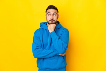 Young caucasian handsome man isolated on yellow background having doubts and thinking