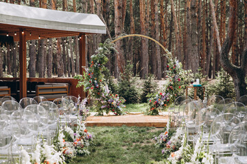 The wedding ceremony area on a green glade in the forest is decorated with designer compositions of flowers and greenery. rustic style