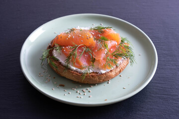 half a bun, greased with fresh cream, smoked fish and fresh dill on a plate