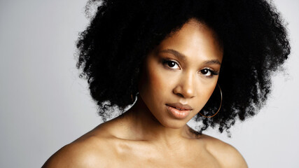 Healthy, Clean, perfect facial skin. Beauty Portrait of a young female model of Afro-appearance posing. Working in a photo studio on a white background. Black healthy curly hair