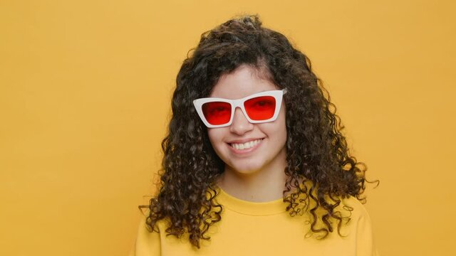 Dancing Happy Brazilian Young Woman Waving his Head Moves Rhythmically to Music Sings Slow Motion on Yellow Background Close-up. Portrait Glamorous, Girl Dancing in sunglasses. Positive Emotions
