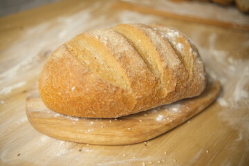Bread freshly baked on a wooden table. Flour, bakery. The cooking process is captured in 4k resolution. Selective focus. Round loaf