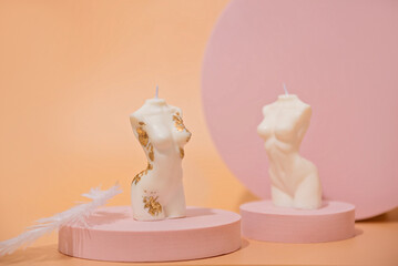 Two trendy soy candle female bodies with silver leaf on a pink podium