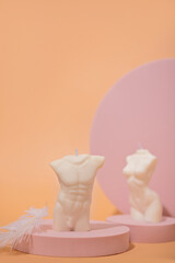 Two trendy soy candle female and male bodies with silver leaf on a pink podium