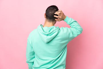 Young caucasian handsome man isolated on pink background in back position and thinking